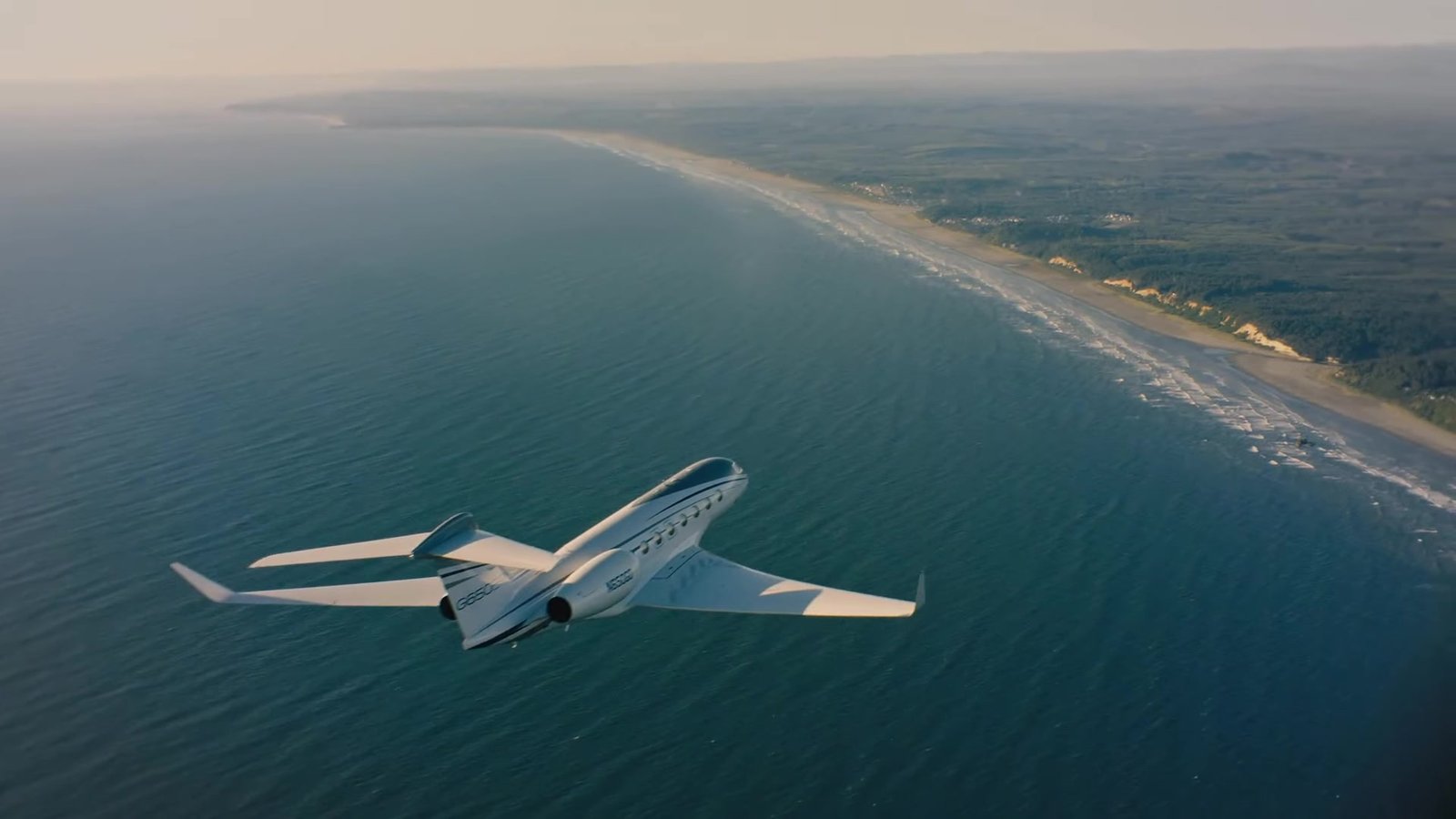 A private jet flying above a sunlit coastline